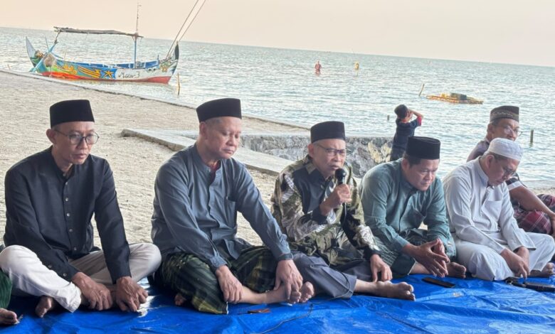 Sejumlah pria berkopiah duduk bersila di tepi pantai mendengarkan penyampaian dalam sebuah acara di pinggir laut.