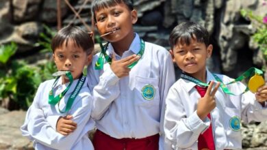 Tiga siswa MI Muhammadiyah Purwodadi mengenakan seragam sekolah sambil memamerkan medali kejuaraan pencak silat Temanggung Open Championship.