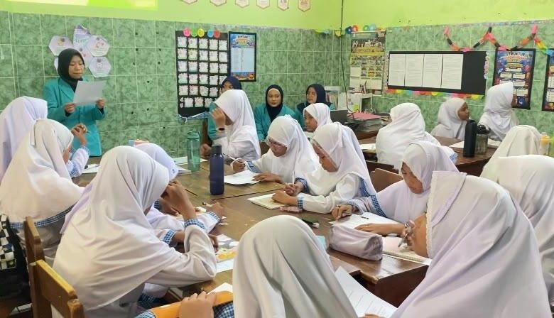 Tim pengabdi UMS mendampingi siswa MI Muhammadiyah Gedongan dalam sesi pengerjaan lembar kerja edukasi pemilahan sampah di ruang kelas.