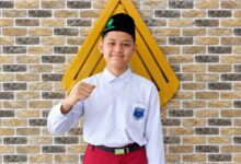 Siswa MI Muhammadiyah Kauman Wiradesa Ghozian Fatihul Haq mengepalkan tangan tersenyum berpeci hitam dan berseragam sekolah.