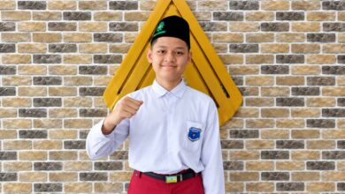 Siswa MI Muhammadiyah Kauman Wiradesa Ghozian Fatihul Haq mengepalkan tangan tersenyum berpeci hitam dan berseragam sekolah.