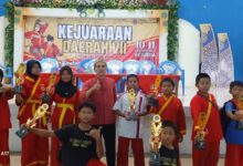 Santri Madin Al Ishlah Dorang berfoto bersama pelatih sambil memegang piala kejuaraan pada Kejurda Tapak Suci Jepara 2026.