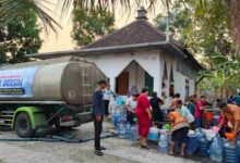 Warga antre mengambil air bersih dari truk tangki bantuan SD Muhammadiyah PK Banyudono di dekat mushola.