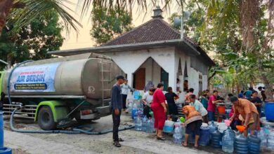 Warga antre mengambil air bersih dari truk tangki bantuan SD Muhammadiyah PK Banyudono di dekat mushola.
