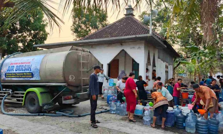 Warga antre mengambil air bersih dari truk tangki bantuan SD Muhammadiyah PK Banyudono di dekat mushola.