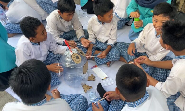 Siswa MI Muhammadiyah Gedongan duduk melingkar sambil mengecat dan menghias galon bekas menjadi tempat sampah edukasi pemilahan sampah UMS.