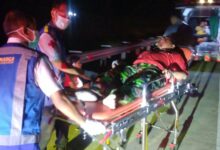 Petugas medis dan Jasa Marga mengevakuasi korban kecelakaan Tol Batang-Weleri dari anggota KOKAM Semarang menggunakan tandu ke dalam ambulans pada malam hari.