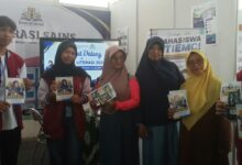 Mahasiswa penjaga stand STIE Muhammadiyah Cilacap memperlihatkan brosur informasi pendaftaran mahasiswa baru di Festival Literasi Cilacap 2026.