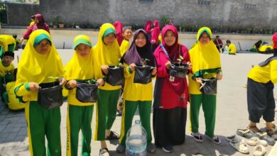 Siswa SDMPK Jogonalan memegang polybag tanaman cabai dalam pelatihan pertanian Milad Muhammadiyah ke-114