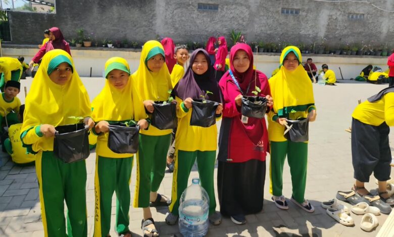 Siswa SDMPK Jogonalan memegang polybag tanaman cabai dalam pelatihan pertanian Milad Muhammadiyah ke-114