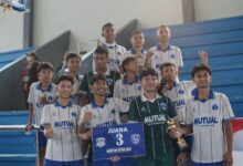 Tim futsal SMP Mutual Magelang berfoto bersama sambil memegang piala dan papan Juara 3 MGMP Cup Futsal 2026 di tribun GOR Samapta.