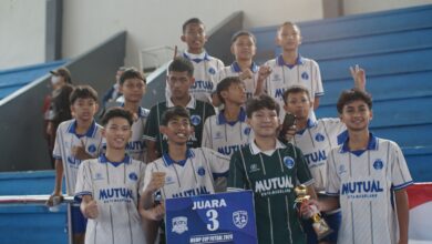Tim futsal SMP Mutual Magelang berfoto bersama sambil memegang piala dan papan Juara 3 MGMP Cup Futsal 2026 di tribun GOR Samapta.