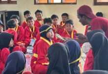 Mahasiswa asing UMS memegang mikrofon dan mengajarkan bahasa Inggris kepada siswa MIM Trangsan berseragam Tapak Suci.