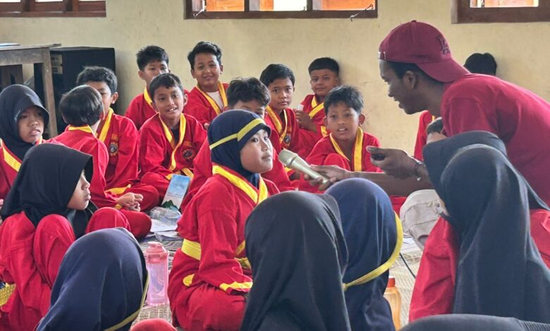 Mahasiswa asing UMS memegang mikrofon dan mengajarkan bahasa Inggris kepada siswa MIM Trangsan berseragam Tapak Suci.