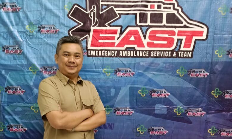 Dosen FIKes UMP Endiyono bersedekap dada di depan latar spanduk pelatihan Emergency Ambulance Service and Team (EAST) RSUD Dr Soetomo Surabaya.