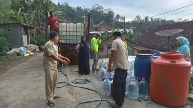 Petugas dan relawan menyalurkan bantuan air bersih dari tangki truk ke galon dan drum milik warga di Temanggung.