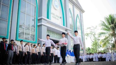 Petugas santri membawa bendera Merah Putih saat upacara Hari Santri Nasional 2026 di halaman Gedung Ahmad Dahlan Ponpes Darul Arqom Patean.