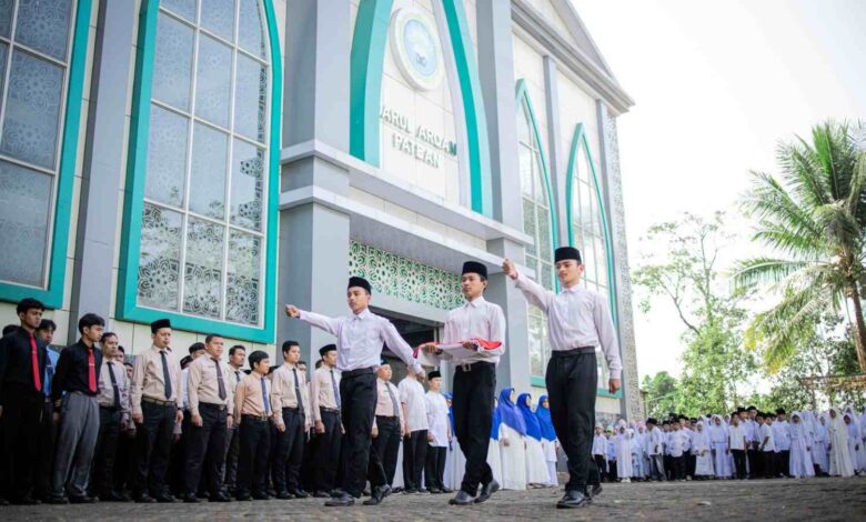 Petugas santri membawa bendera Merah Putih saat upacara Hari Santri Nasional 2026 di halaman Gedung Ahmad Dahlan Ponpes Darul Arqom Patean.