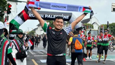Peserta mengangkat syal bertuliskan #SavePalestine dalam ajang Run for Palestine Yogyakarta 2026 di Titik Nol Kilometer.