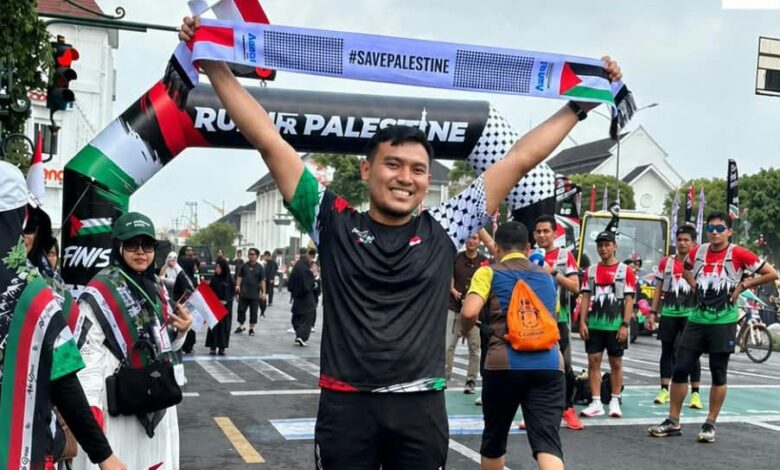 Peserta mengangkat syal bertuliskan #SavePalestine dalam ajang Run for Palestine Yogyakarta 2026 di Titik Nol Kilometer.